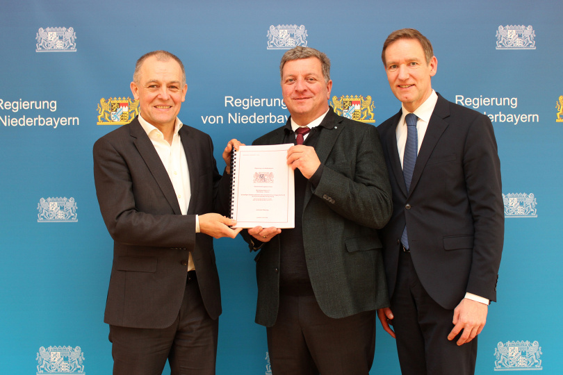 Der Bayerische Staatsminister für Wohnen, Bau und Verkehr, Christian Bernreiter (Mitte), und Regierungspräsident Rainer Haselbeck (rechts) überreichen dem Direktor der Niederlassung Südbayern der Autobahn GmbH des Bundes, Michael Kordon, den Planfeststellungsbeschluss. Foto: Regierung von Niederbayern