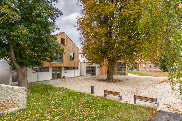 Durch die Baukörperanordnung konnten die zwei großen Bestandsbäume am Vorplatz erhalten und in die Außenraumgestaltung einbezogen werden. FOTOS: RALF KUHN